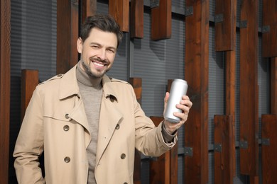 Happy man holding tin can with beverage outdoors. Space for text