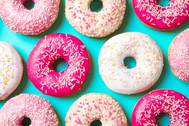 Photo of Delicious glazed doughnuts on color background, top view