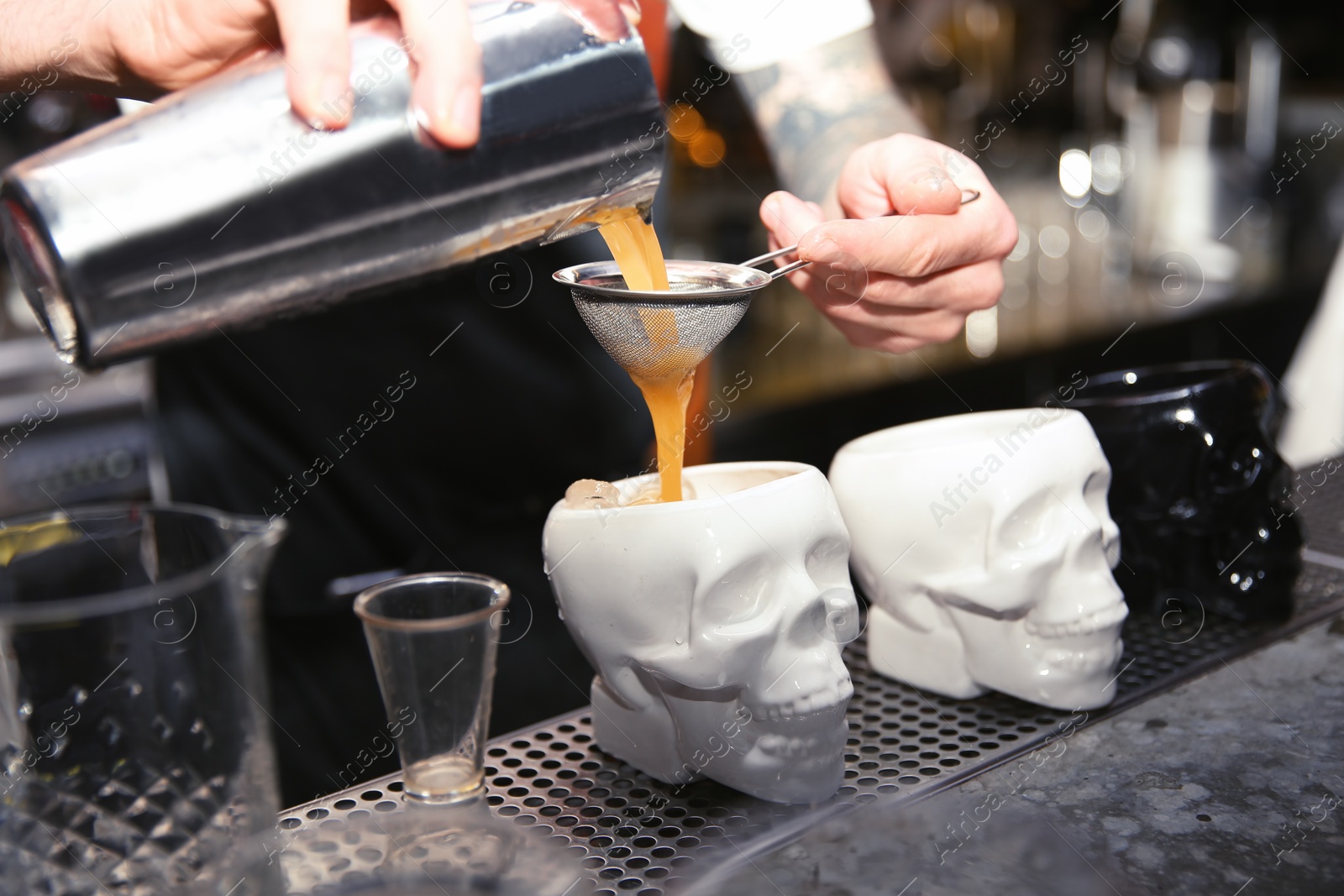 Photo of Bartender pouring tasty cocktail at counter in nightclub, closeup