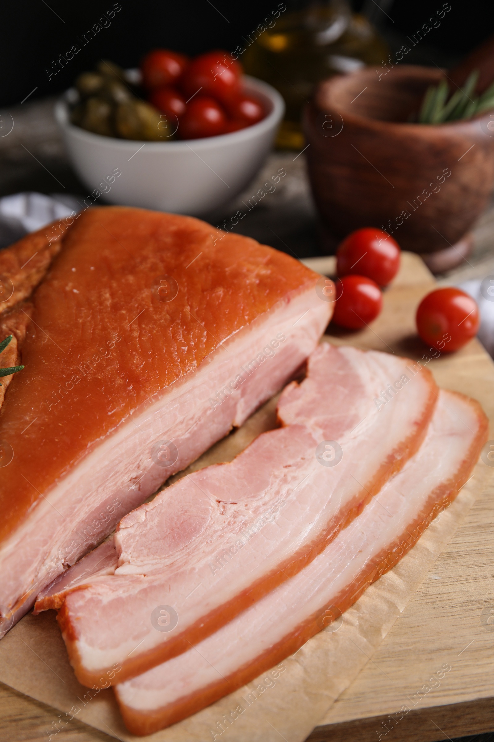 Photo of Delicious smoked bacon with rosemary on wooden board, closeup