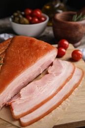 Photo of Delicious smoked bacon with rosemary on wooden board, closeup