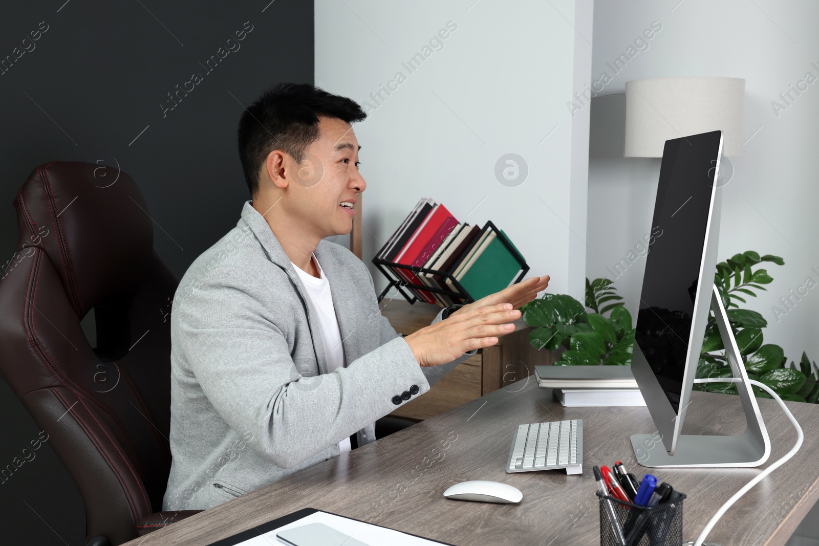 Photo of Emotional boss having online meeting via computer at wooden table in modern office