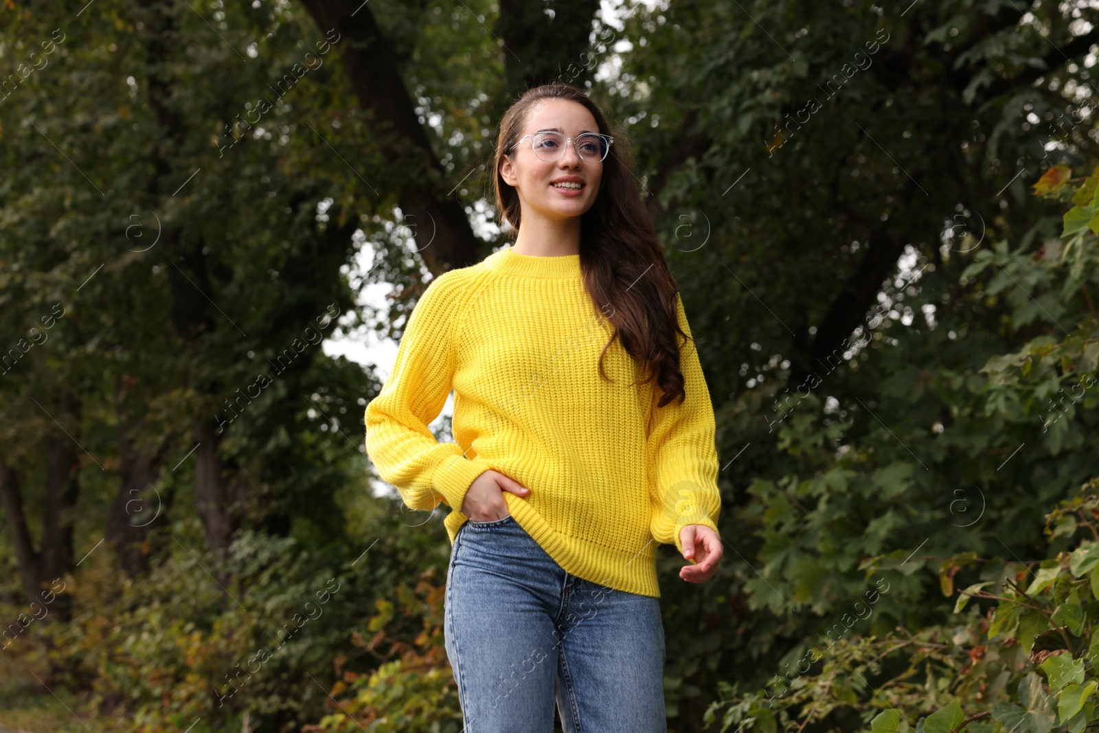 Photo of Beautiful young woman in stylish warm sweater walking outdoors, low angle view