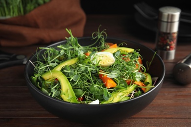 Photo of Salad with fresh organic microgreen in bowl on wooden table, closeup