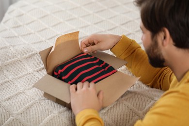 Photo of Man opening parcel at home. Internet shopping