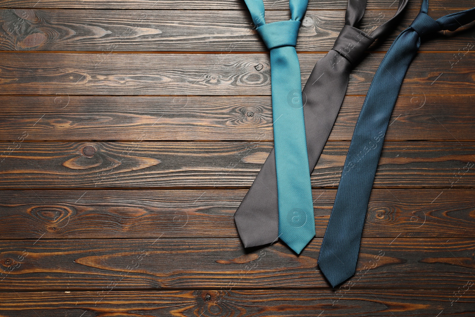 Photo of Different neckties on wooden table, flat lay. Space for text