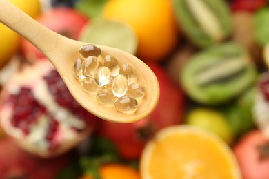 Photo of Vitamin pills in spoon over fresh fruits, top view. Space for text