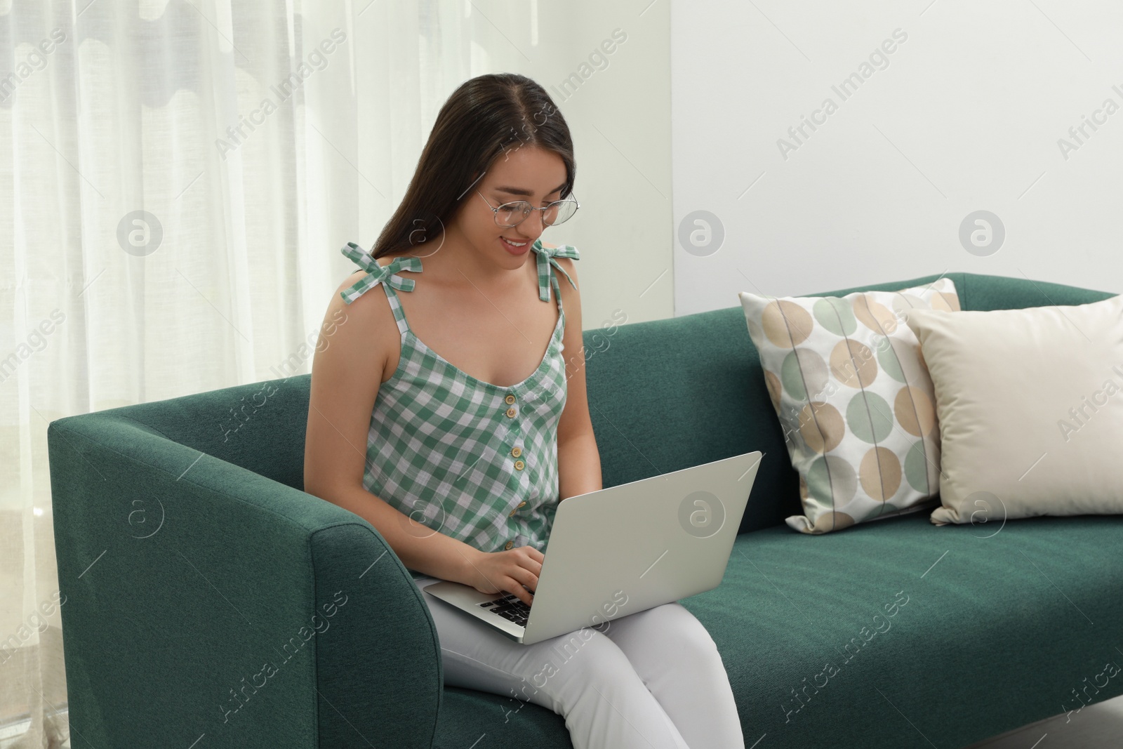 Photo of Young woman using laptop on sofa at home. Internet shopping