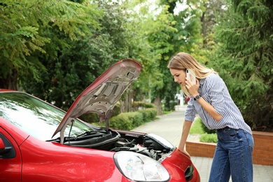 Woman talking on phone near broken car outdoors