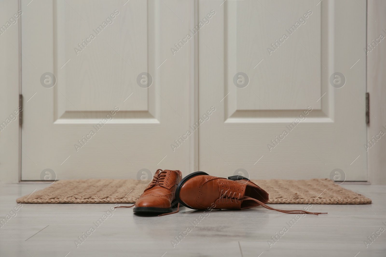 Photo of Stylish shoes on door mat in hall