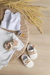 Photo of Baby bodysuit, hat, booties, toy and spikelets on wooden background, flat lay