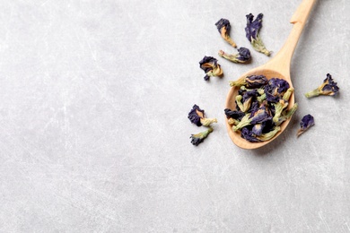 Photo of Spoon and dry organic blue Anchan on light grey table, flat lay with space for text. Herbal tea