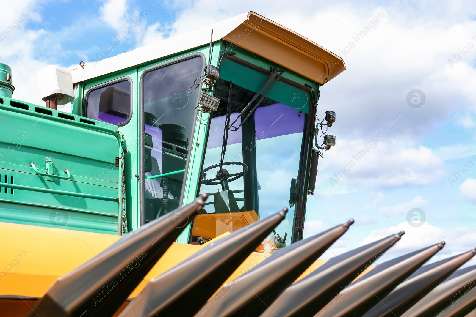 Photo of Modern combine harvester against blue sky with white clouds