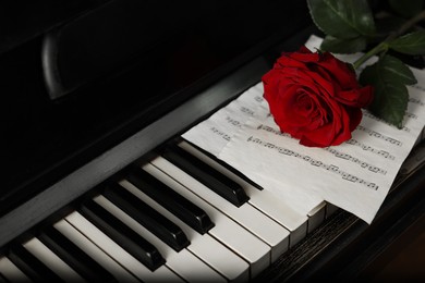 Photo of Beautiful red rose and musical notes on piano keys