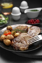 Photo of Tasty beef tongue pieces, rosemary and potatoes on grey table, closeup