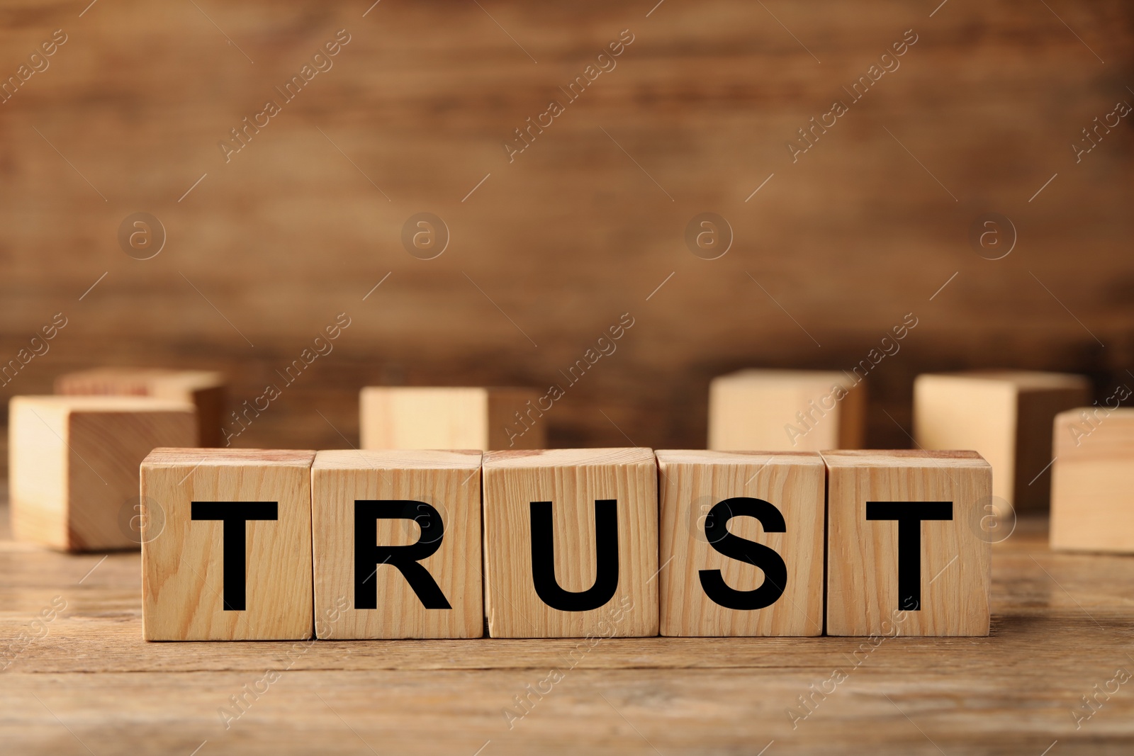 Photo of Cubes with word TRUST on wooden table. Space for text