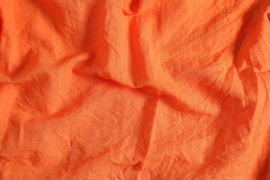 Photo of Crumpled orange fabric as background, top view