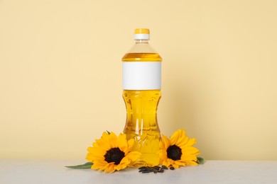 Photo of Bottle of cooking oil, sunflowers and seeds on white table
