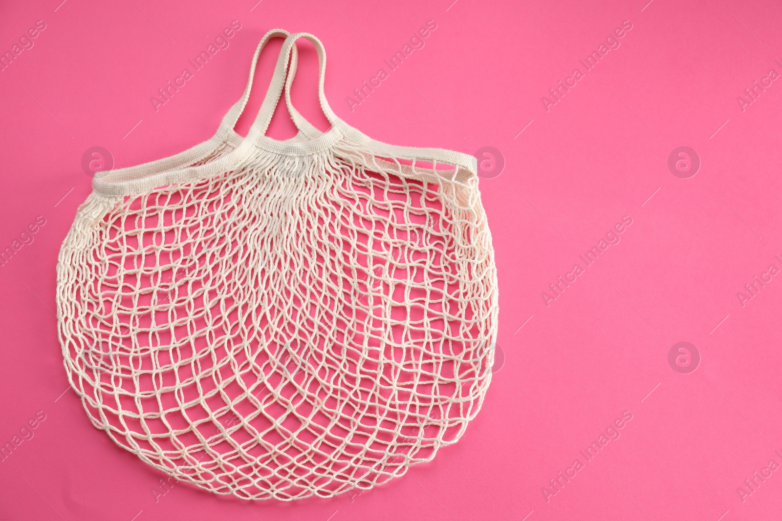 Photo of White string bag on bright pink background, top view. Space for text