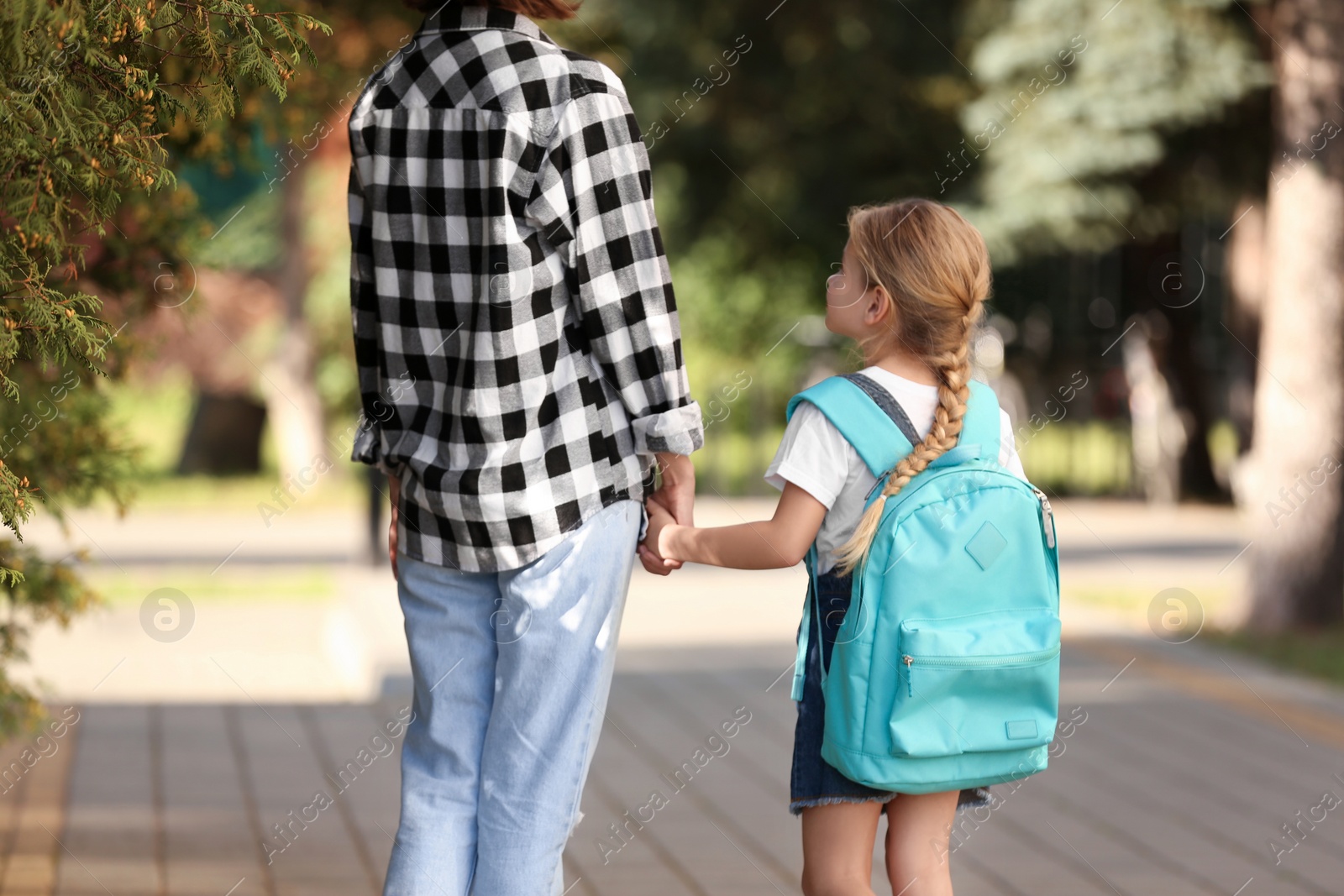 Photo of Little girl with her mother on way to school, back view