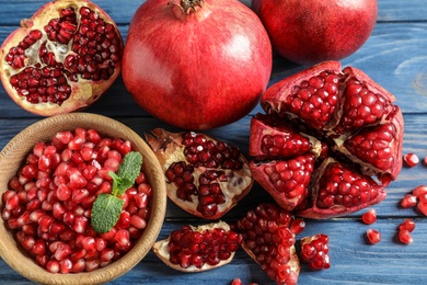 Bowl with seeds and ripe pomegranates on wooden background, top view