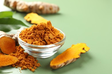 Photo of Aromatic turmeric powder and raw roots on green background, closeup. Space for text