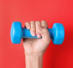 Photo of Woman holding vinyl dumbbell on color background, closeup