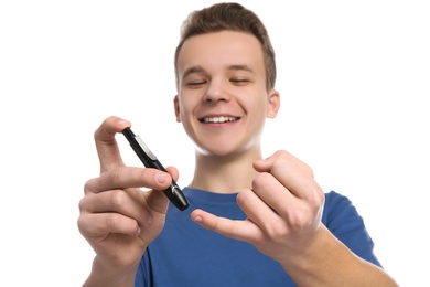 Teen boy using lancet pen on white background. Diabetes control