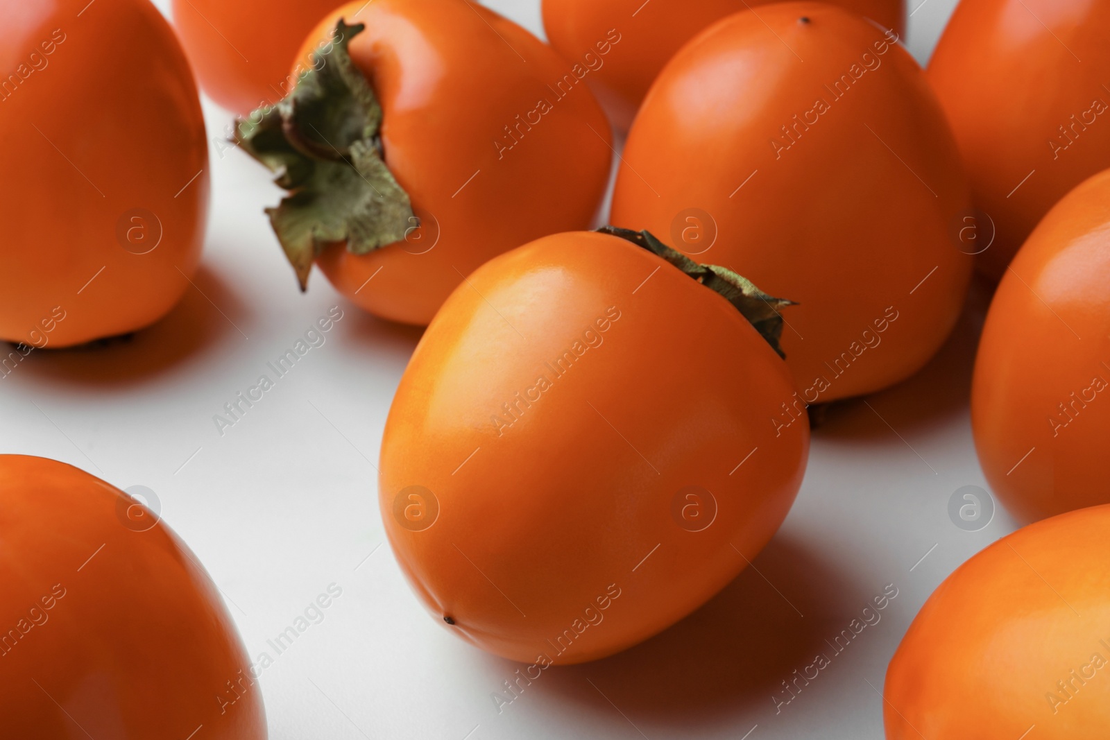 Photo of Delicious ripe juicy persimmons on white table