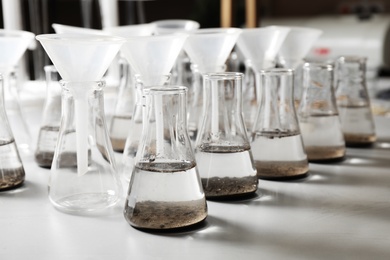 Laboratory glassware with soil extracts and funnels on table