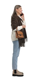 Photo of Senior woman with bag talking on smartphone against white background