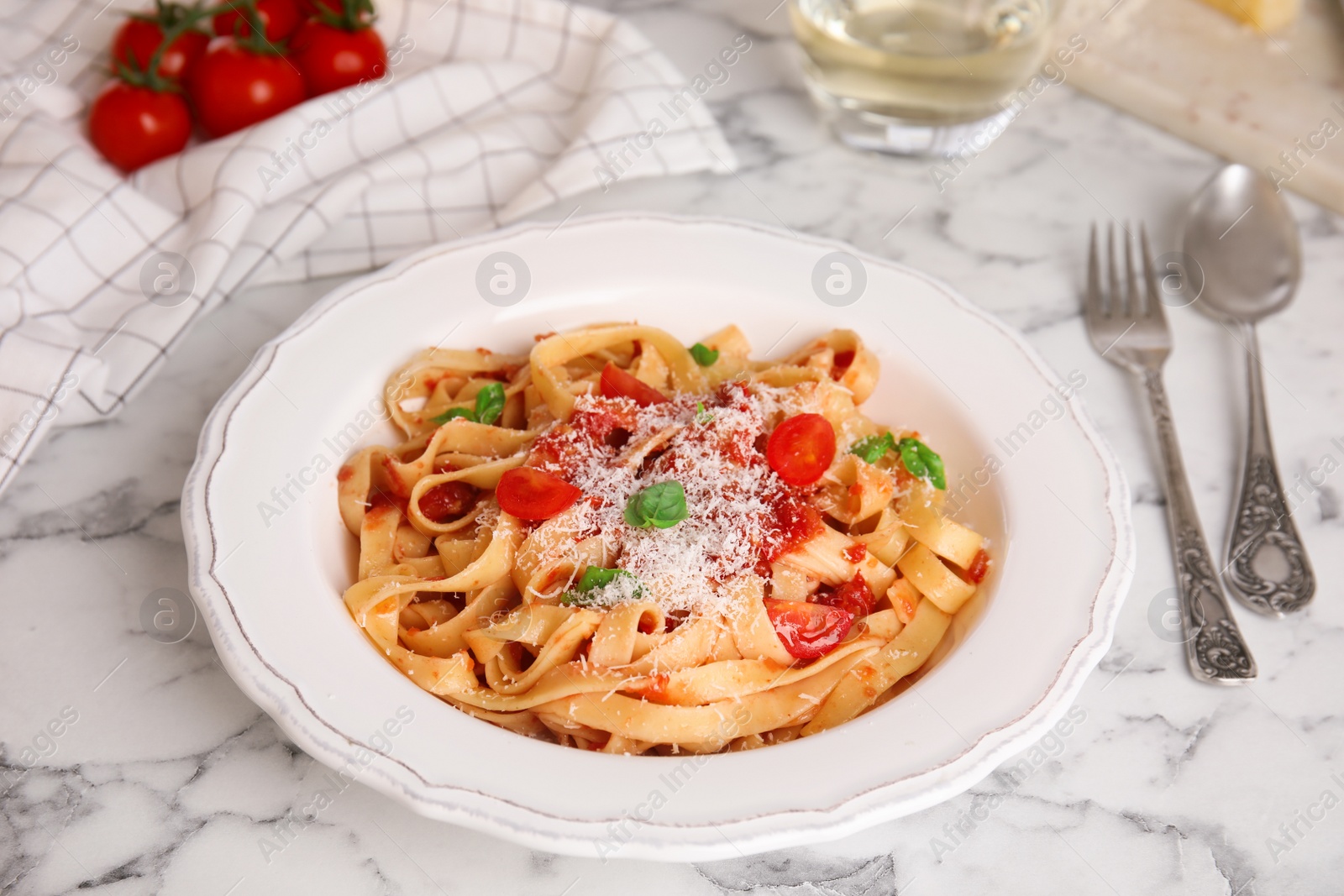 Photo of Tasty pasta with tomatoes, cheese and basil on white marble table