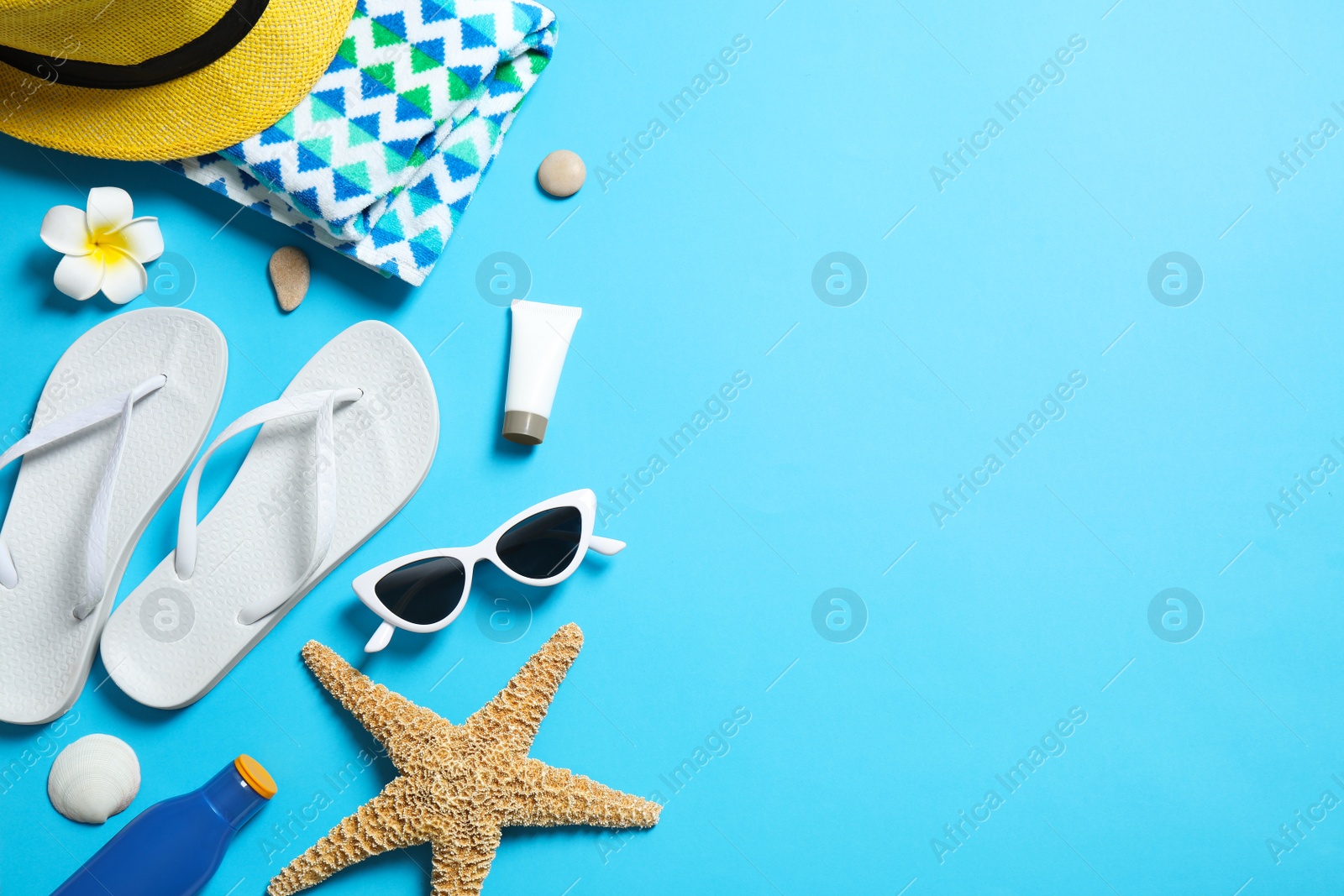 Photo of Flat lay composition with stylish beach accessories on light blue background, space for text