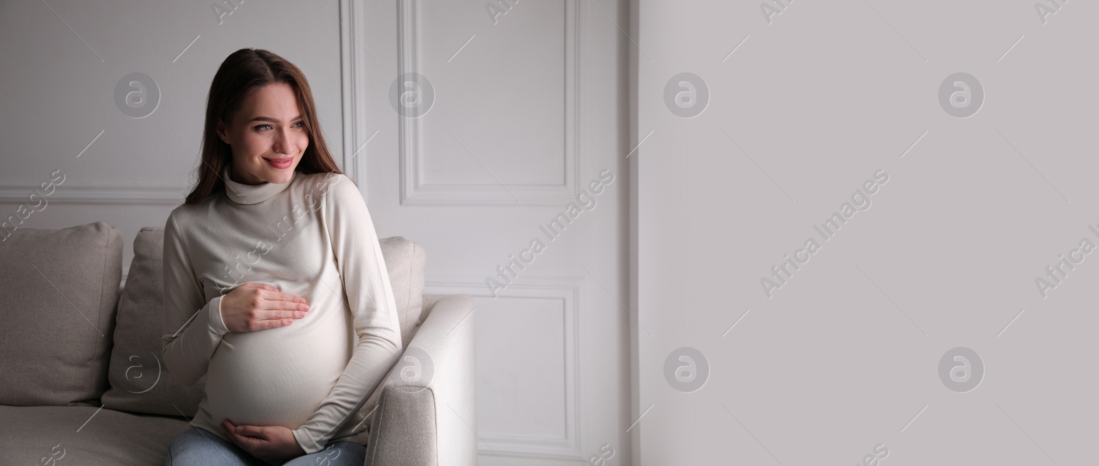 Image of Young pregnant woman sitting on sofa at home, space for text. Banner design