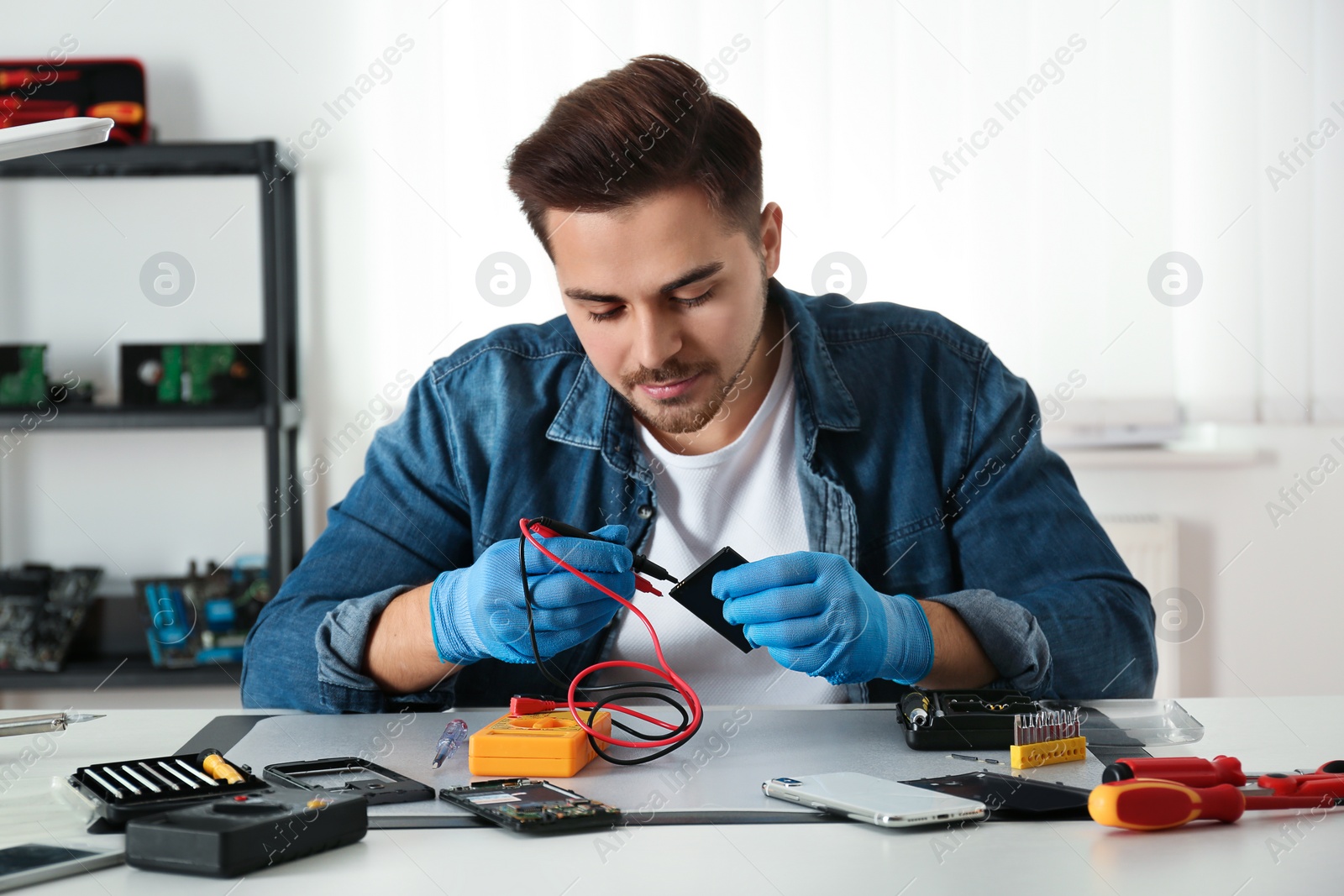 Photo of Technician checking broken smartphone at table in repair shop