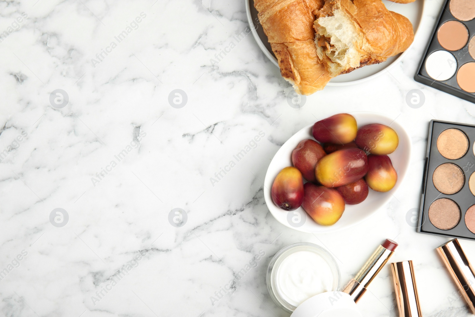 Image of Fresh ripe palm oil fruits, croissant and cosmetic products on white marble table, flat lay. Space for text