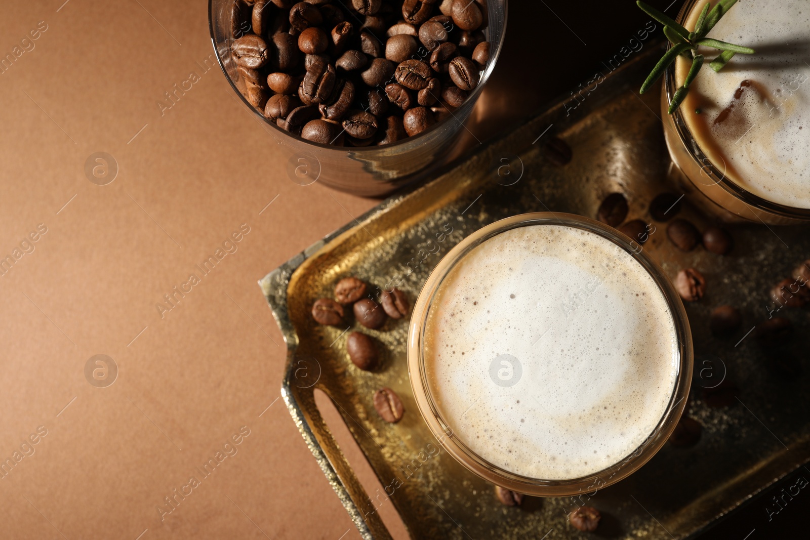 Photo of Refreshing iced coffee with milk in glasses on brown table, flat lay. Space for text