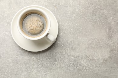 Cup of aromatic coffee on light grey table, top view. Space for text