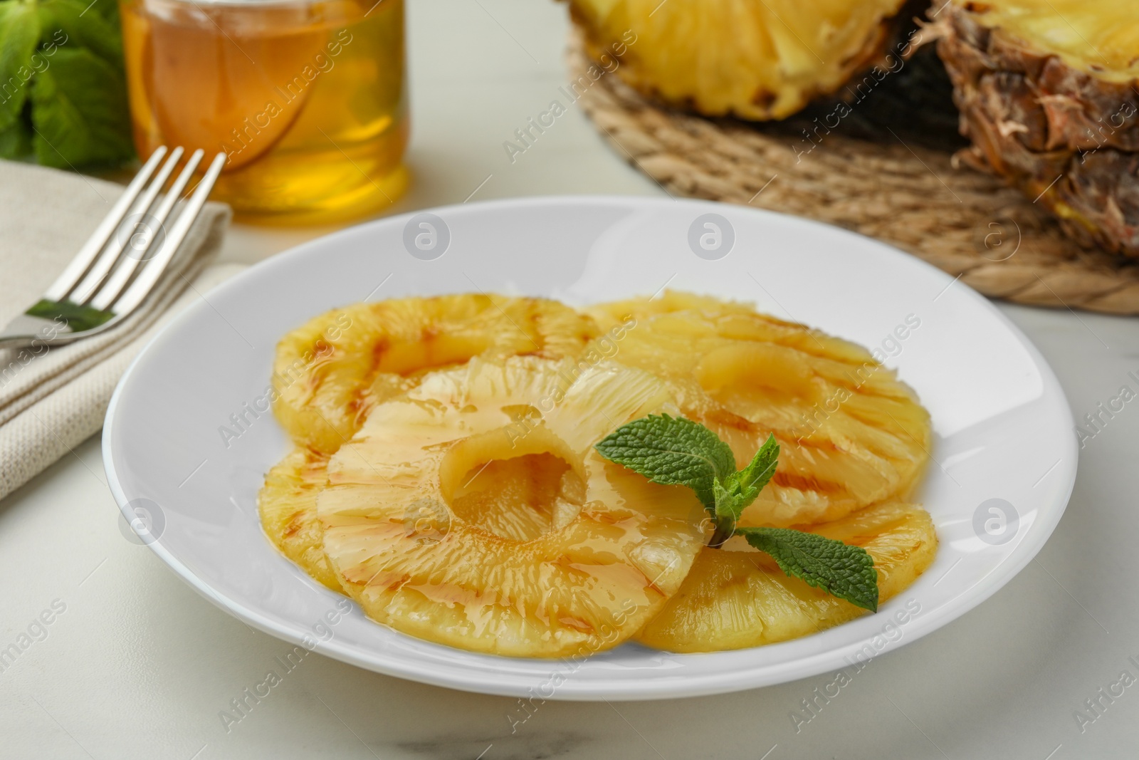 Photo of Tasty grilled pineapple slices with mint on white table, closeup