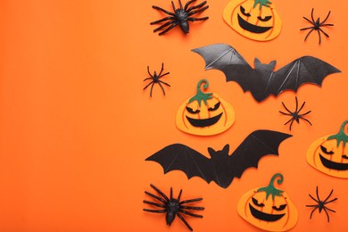 Flat lay composition with cardboard bats, felt pumpkins and spiders on orange background, space for text. Halloween celebration