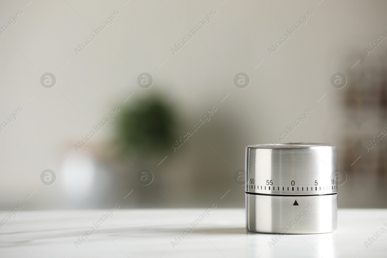 Photo of Kitchen timer on white marble table against blurred background. Space for text