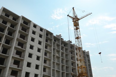 Photo of Unfinished building and construction crane outdoors, low angle view