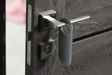 Photo of Wooden door with blank hanger on metal handle, closeup