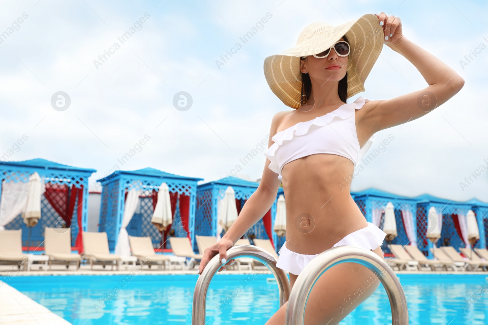 Photo of Young woman in stylish white bikini near swimming pool. Space for text