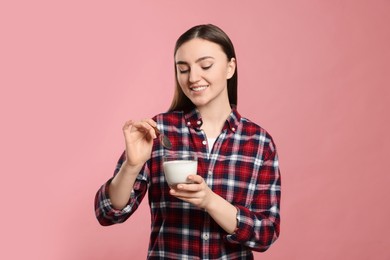 Woman with tasty yogurt on pink background