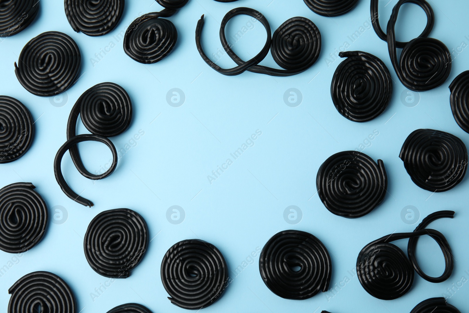 Photo of Tasty liquorice candies on light blue background, flat lay. Space for text