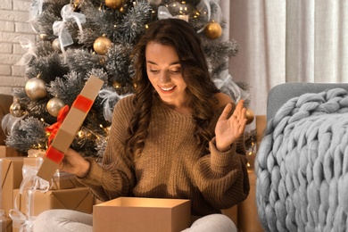 Image of Happy young woman opening Christmas gift at home. Magic holiday 