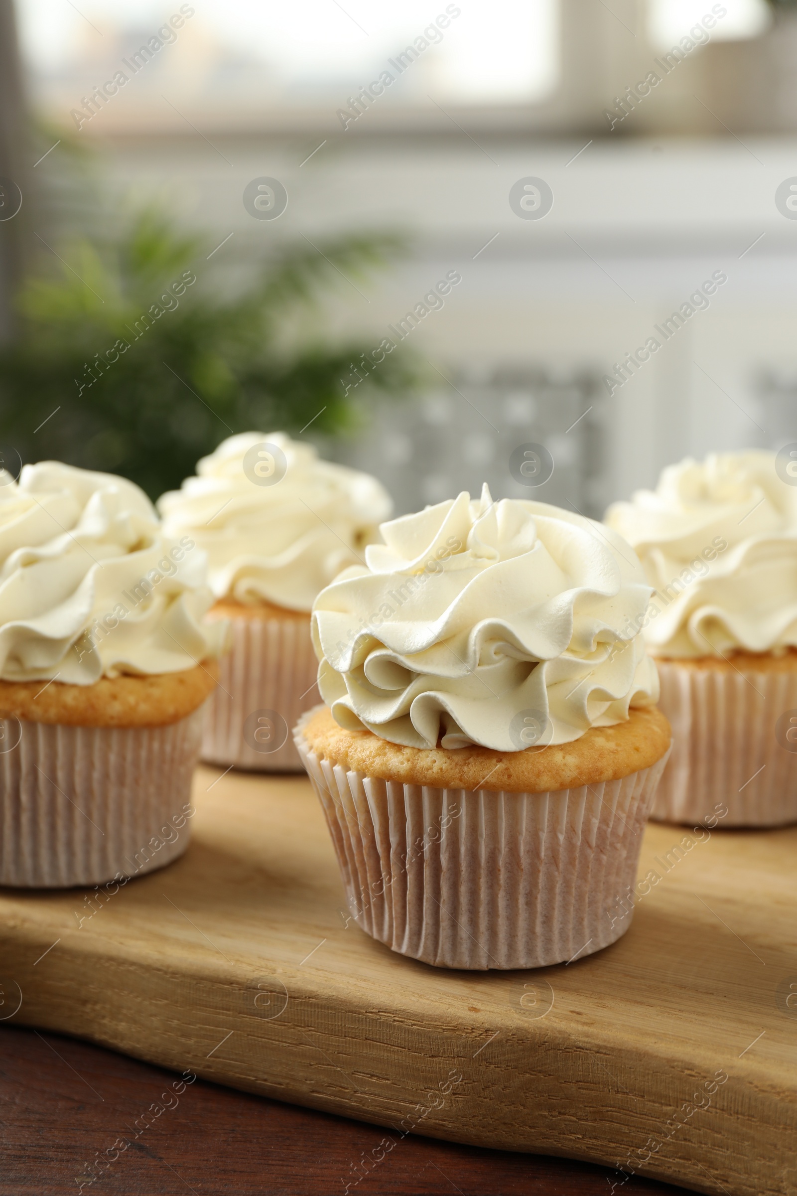 Photo of Tasty cupcakes with vanilla cream on wooden table, closeup