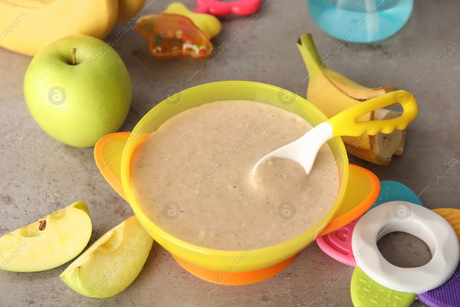 Photo of Bowl with healthy baby food on gray table