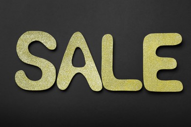 Photo of Word Sale made of golden letters on dark background, flat lay. Black Friday
